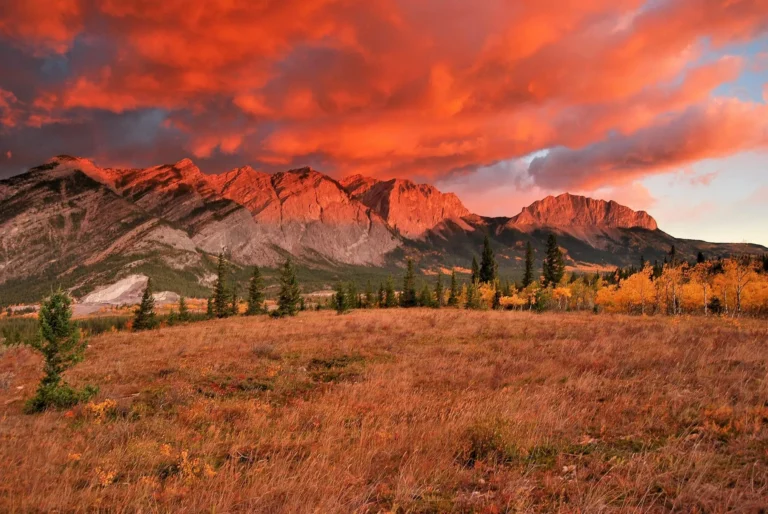 Red sunrise clouds over the Rocky Mountain front ranges and autumn foothills in Alberta