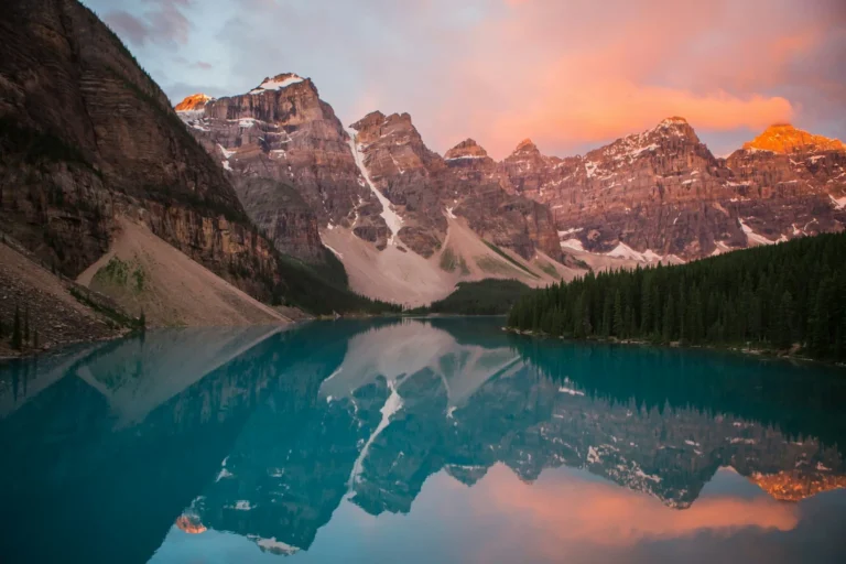 Alpenglow on snowy peaks above a mountain lake