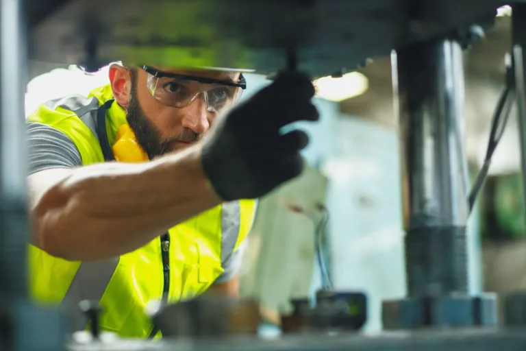 Technician in hi-vis tightening fittings on plant equipment
